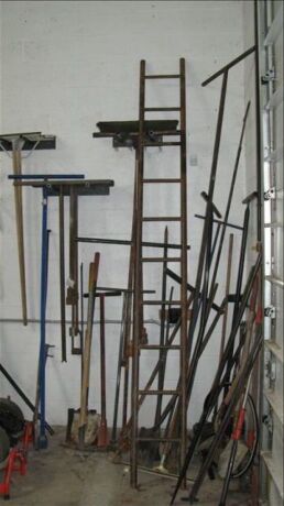 Lot -- shovels, post hole digger, pick, brooms, etc on wall *** PLEASE NOTE: This lot is offered subject to bulk bid offer on lot 118